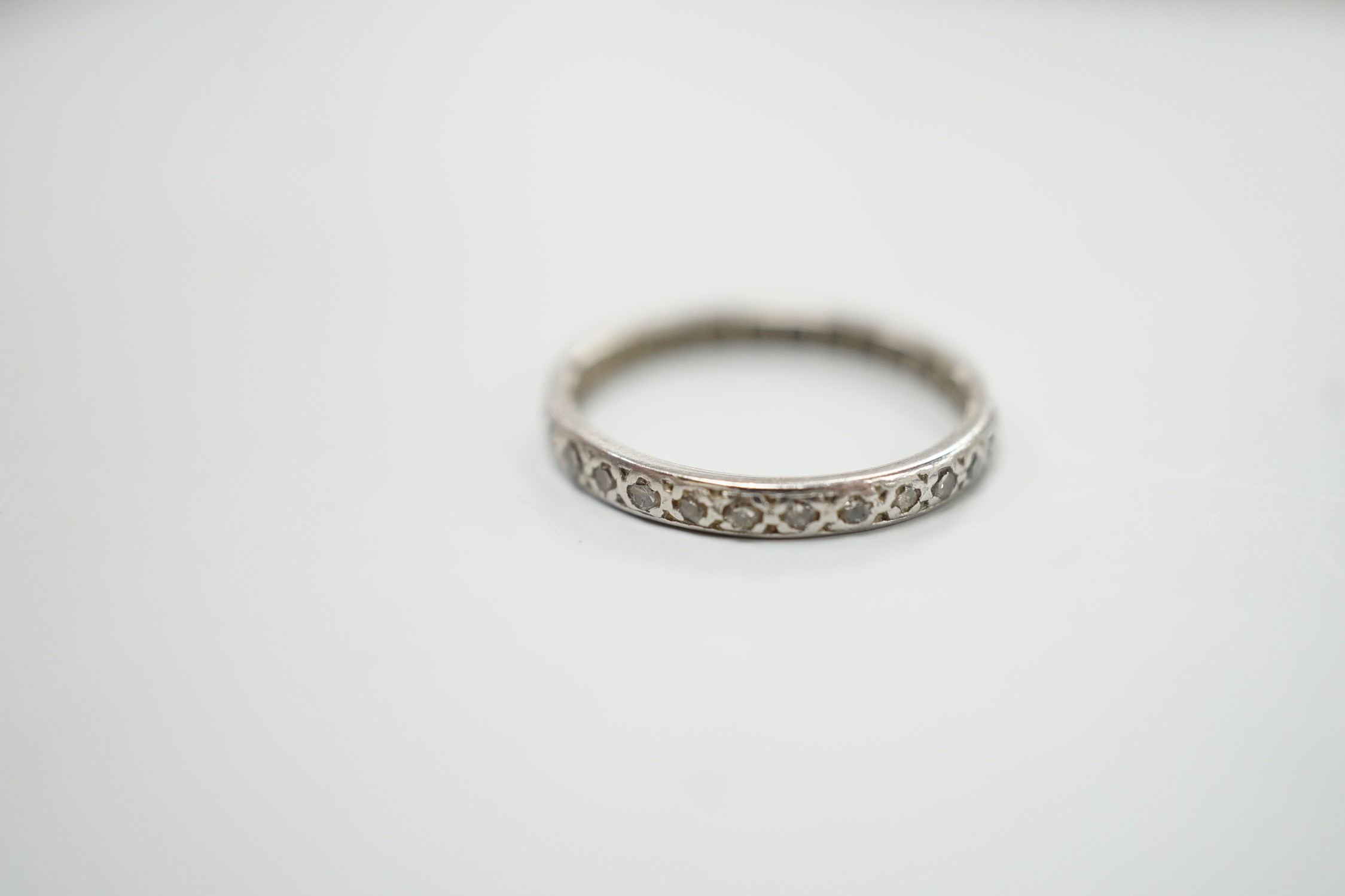 A white metal and diamond chip set full eternity ring, size K, gross weight 1.8 grams.